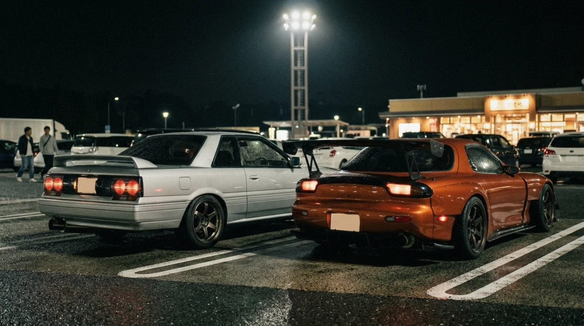 A silver coupe and an orange RX-7 parked side by side at the floodlit meet on a Nissan GT-R experience in Tokyo